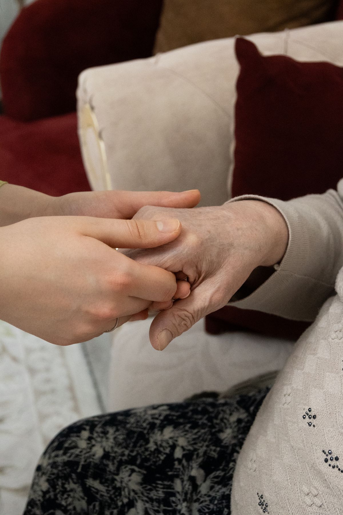 A volunteer gently holding the hands of an elderly neighbor