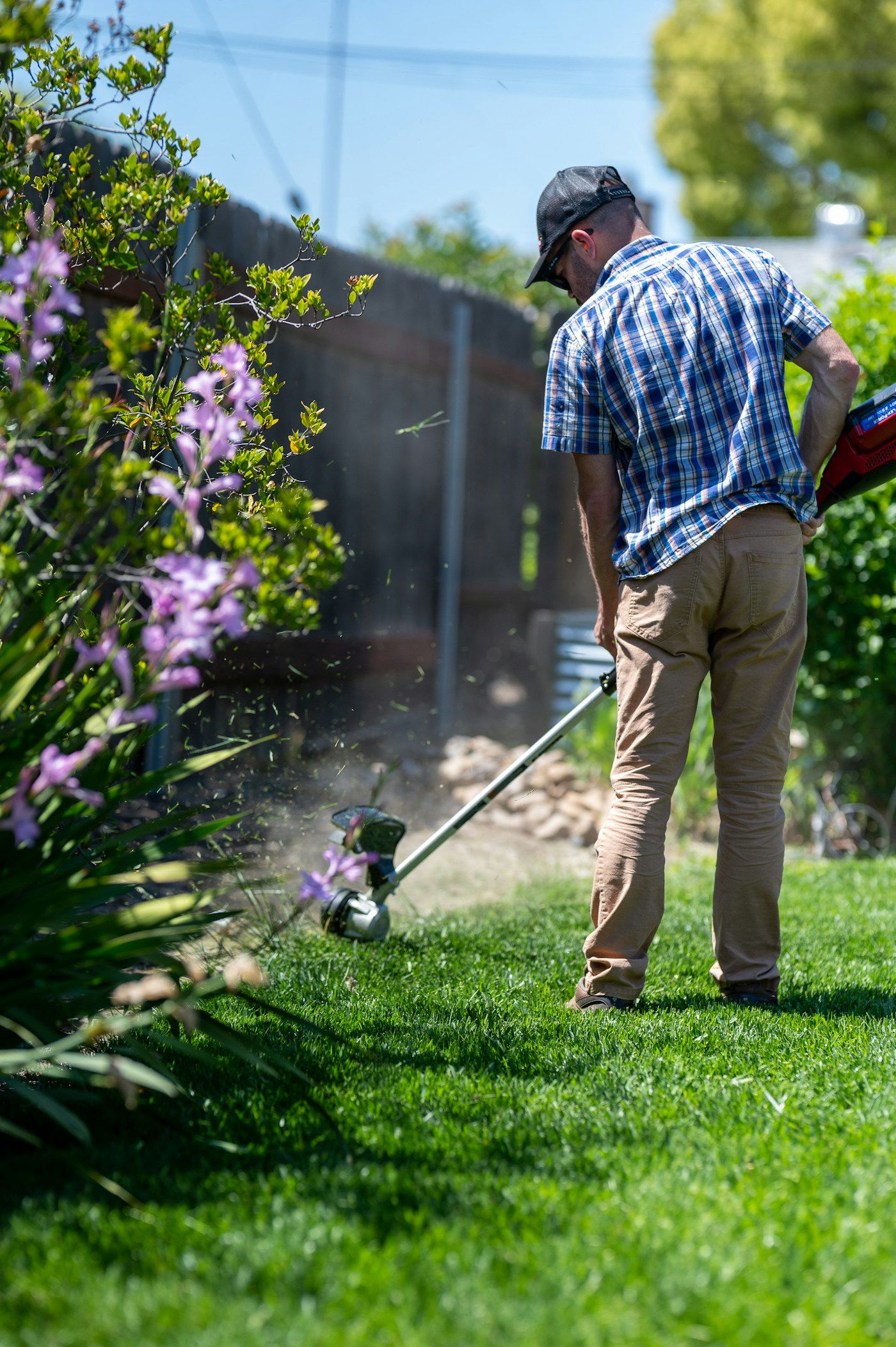 A volunteer edging and trimming a neighbor's lawn